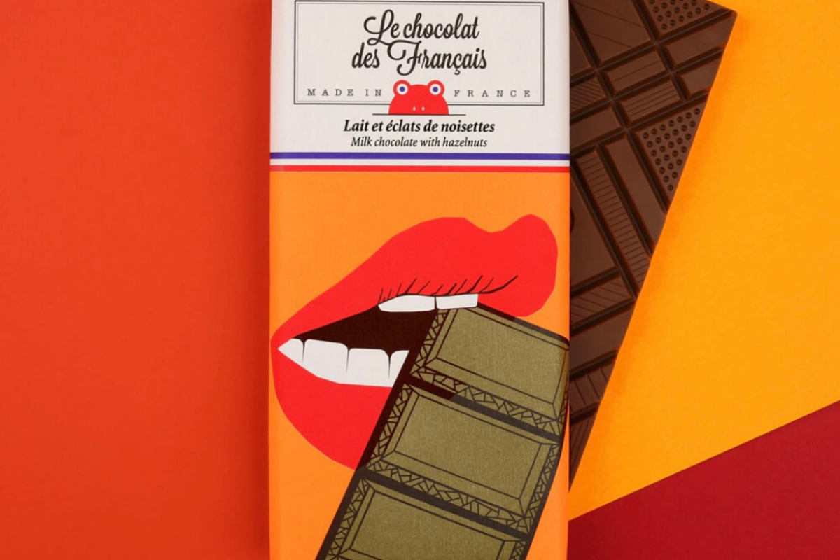 Tablette de chocolat au lait aux éclats de noisettes croquantes, fabriquée en France par Le Chocolat des Français. Chocolat artisanal fondant, avec un packaging illustré coloré et original.
